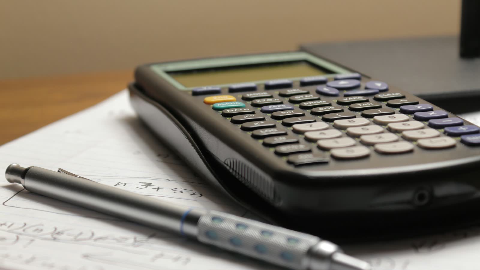 Calculatrice et stylo posés sur une feuille de notes